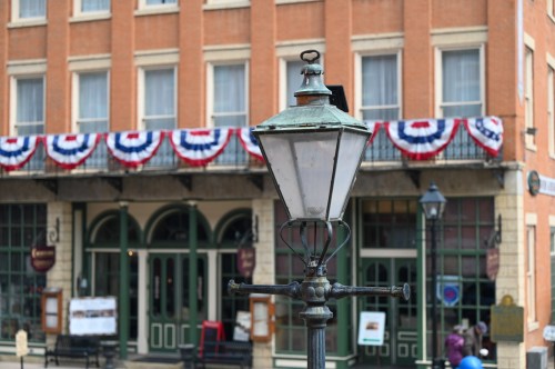 A vintage street lamp in front of a building decorated with red, white, and blue bunting.