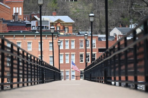 A view down a bridge leading to buildings, with an American flag visible among the structures in the background.