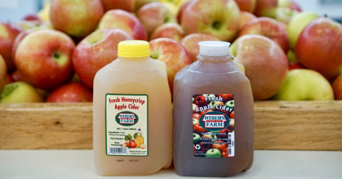 two small bottles/pints of cider in front of a tray with a pile of apples on top from Weber's Cider Mill Farm
