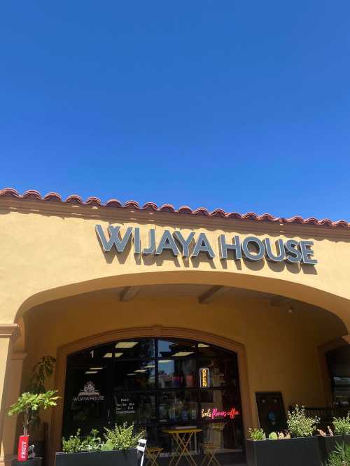 Sign for "Wijaya House" on a yellow building under a clear blue sky.