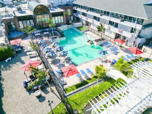 Aerial view of a hotel pool area with lounge chairs, umbrellas, and landscaped gardens.