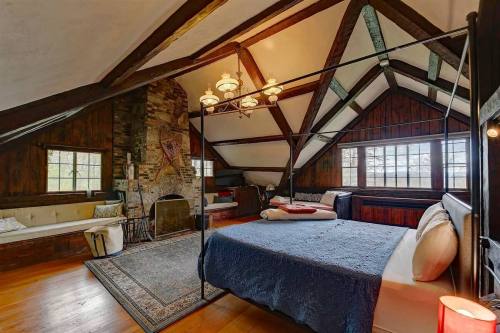 Cozy bedroom with a four-poster bed, wooden beams, a fireplace, and large windows overlooking a scenic view.