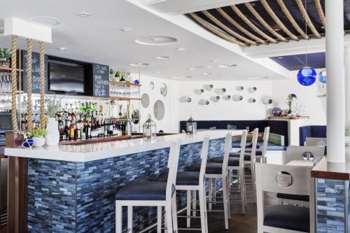 Modern bar interior with a sleek counter, high stools, and decorative mirrors, featuring a well-stocked liquor display.