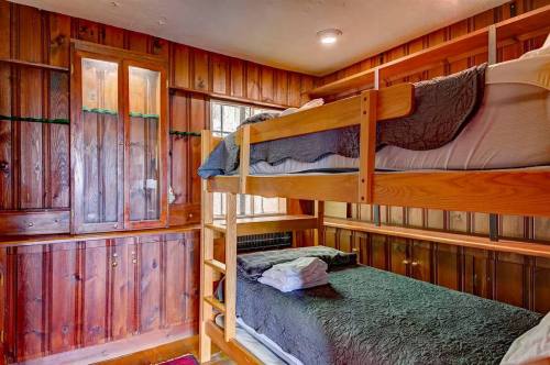 Cozy bedroom with wooden walls featuring a bunk bed and neatly arranged bedding.