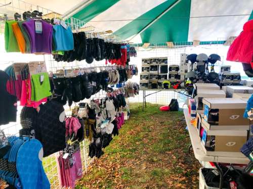 A tent display filled with colorful gloves, hats, and various outdoor gear on tables and hanging racks.