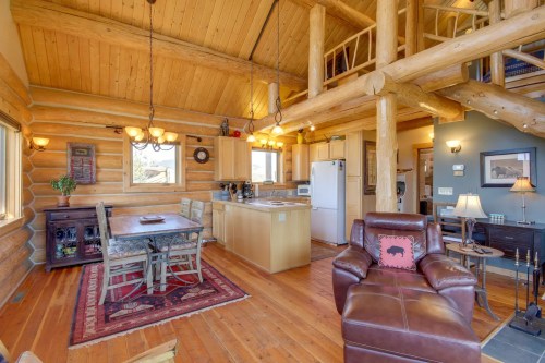 Cozy log cabin interior featuring a kitchen, dining area, and living space with wooden beams and rustic decor.