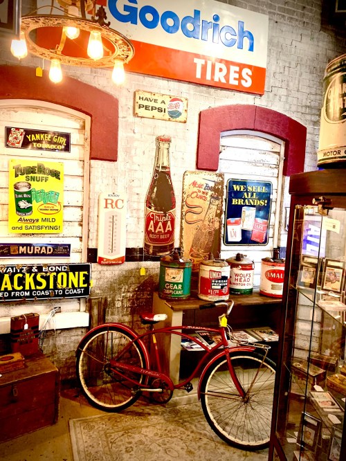 A vintage display featuring a red bicycle, old signs, and memorabilia in a nostalgic setting.