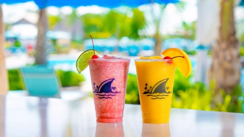 Two colorful tropical drinks with garnishes, set against a blurred poolside background.