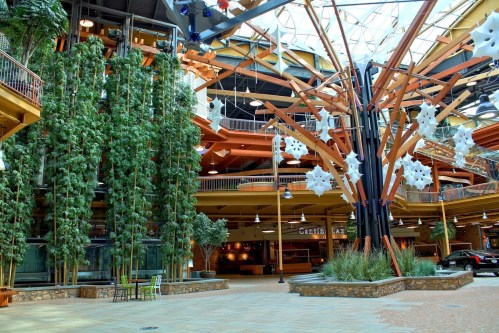 Interior of a spacious atrium with tall trees, modern architecture, and decorative snowflakes hanging from the ceiling.
