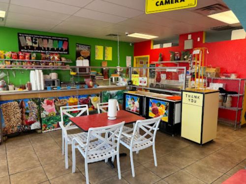 Brightly colored café interior with tables, chairs, and a service counter featuring vibrant wall decorations.
