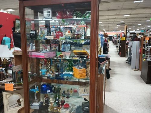 A display case filled with various collectibles and knick-knacks in a thrift store aisle.