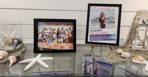 A display featuring a group photo and a framed poster of Taylor Swift, surrounded by seashells and beach decor.