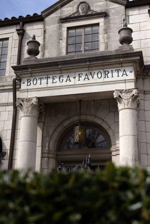 Facade of a building with the sign "Bottega Favorita" above the entrance, featuring decorative columns and a lantern.