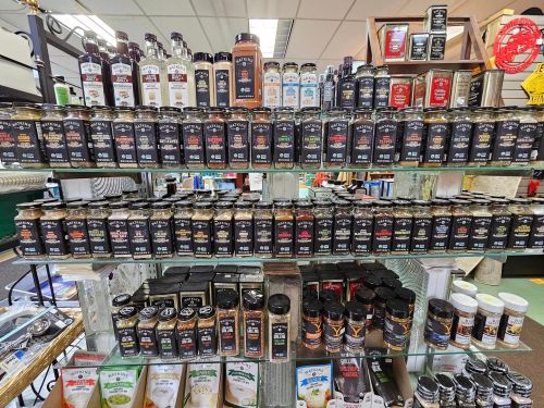 A display shelf filled with various jars and bottles of spices, sauces, and seasonings in a store.