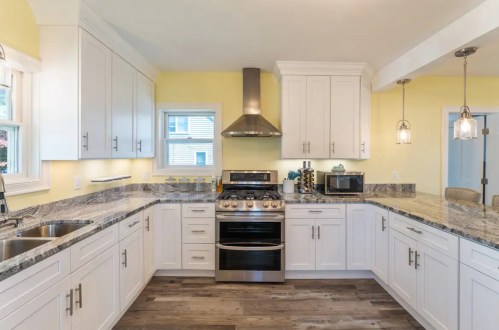 Bright kitchen with white cabinets, granite countertops, stainless steel appliances, and yellow walls.