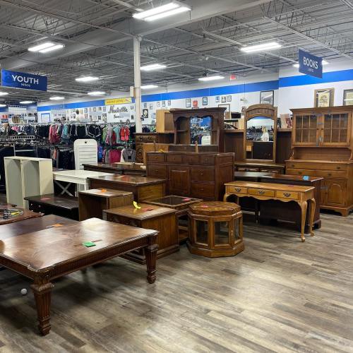 A variety of wooden furniture pieces displayed in a store, including tables, dressers, and cabinets.