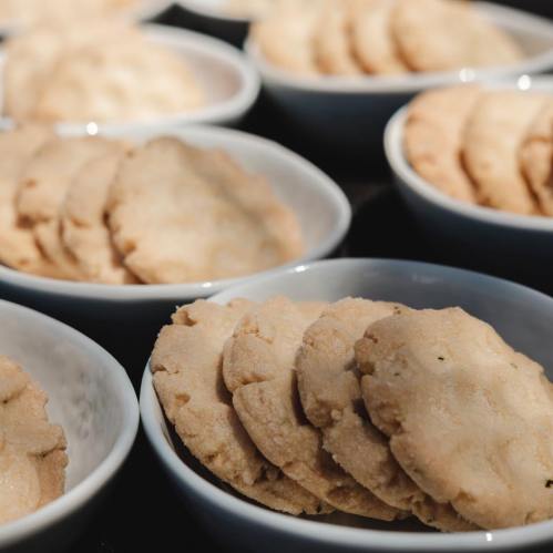 A close-up of multiple bowls filled with round, light-colored cookies arranged neatly.