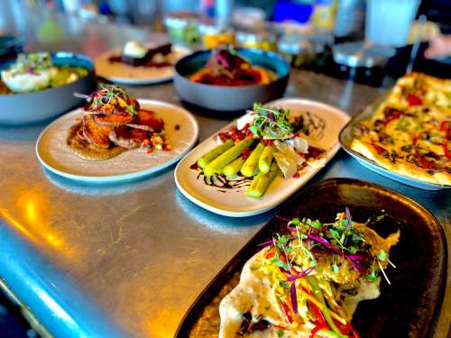 A variety of beautifully plated dishes on a table, featuring vibrant vegetables and garnishes.