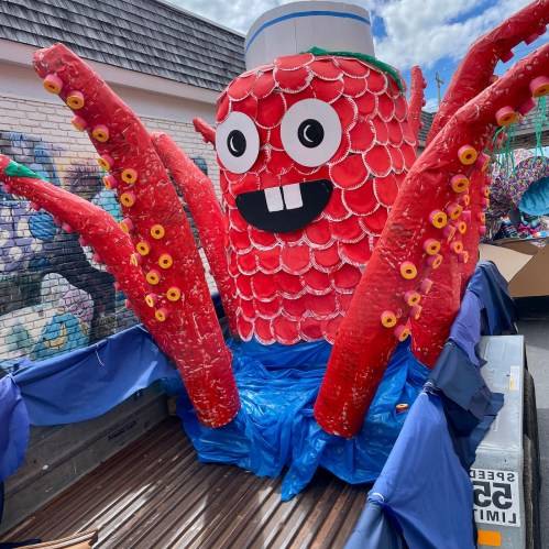 A large, colorful octopus float with a smiling face and bright red tentacles, displayed on a truck bed.