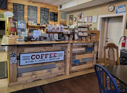 Cozy coffee shop interior featuring a wooden counter, menu boards, and various coffee products on display.