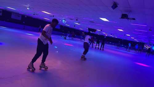 A vibrant roller skating rink with colorful lights and people skating on a smooth surface.