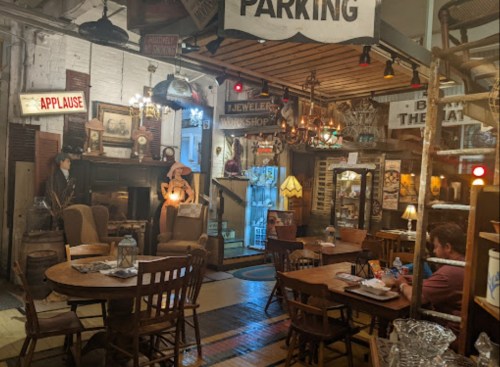 Cozy vintage café with wooden tables, eclectic decor, and a warm atmosphere, featuring a mix of antiques and soft lighting.