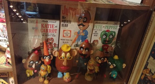 Display case featuring various Mr. Potato Head toys and related merchandise, including colorful characters and packaging.