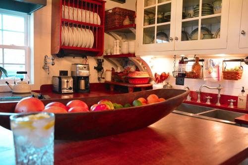 A cozy kitchen with wooden countertops, a fruit bowl, and shelves filled with dishes and kitchenware.