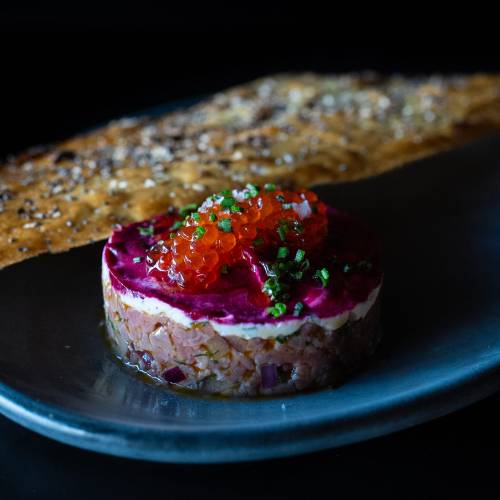 Beef Tartare served on a blue plate topped with caviar