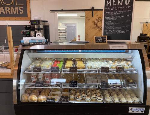 A display case filled with various pastries, desserts, and snacks, with a menu board in the background.