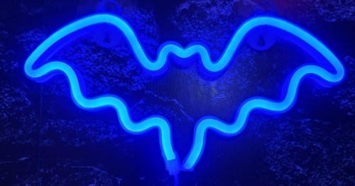A glowing blue neon sign in the shape of a bat against a dark background.