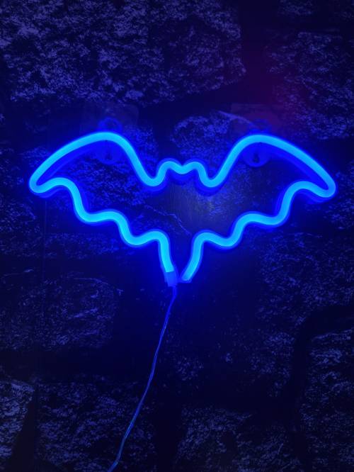 A blue neon sign shaped like a bat against a textured dark wall.