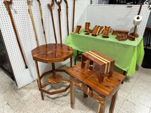 A display of wooden furniture, including tables and decorative items, with walking canes in the background.