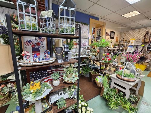 A vibrant display of home decor and plants, featuring shelves with decorative items, flowers, and themed decorations.