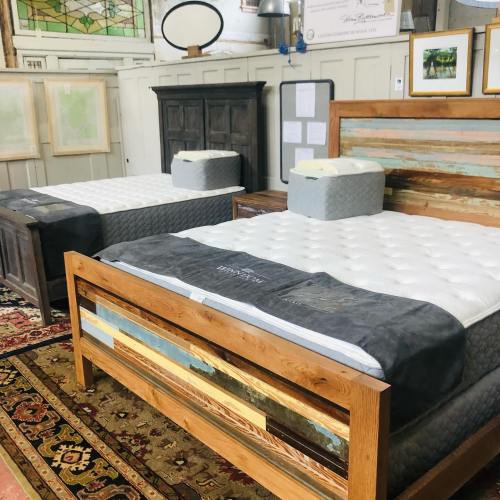 Two wooden beds with mattresses in a cozy room, featuring decorative wall art and a patterned rug.