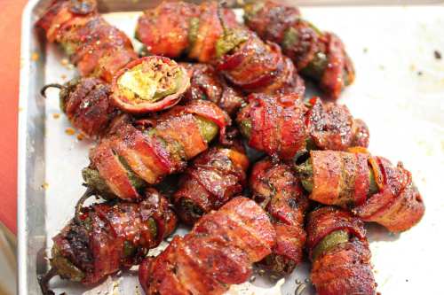 A tray of bacon-wrapped jalapeño poppers, crispy and golden, filled with cheese and spices.
