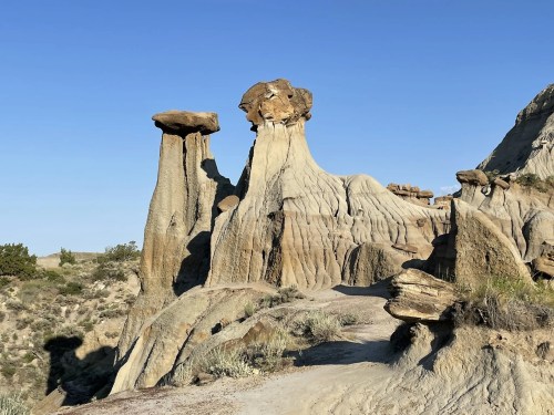 Unique rock formations rise against a clear blue sky, showcasing layered textures and natural erosion patterns.