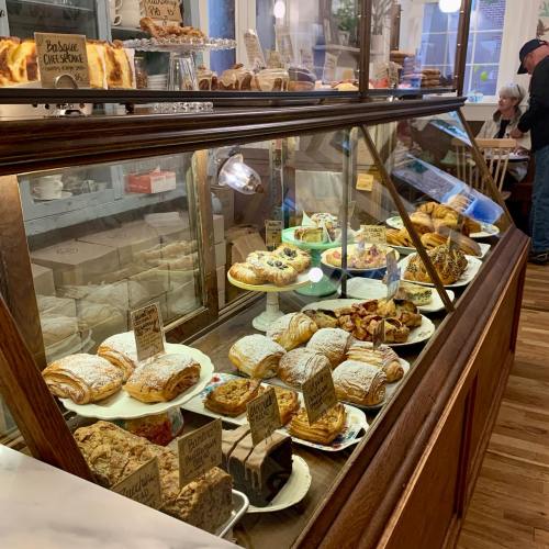 A display case filled with various pastries, cakes, and croissants in a cozy café setting.