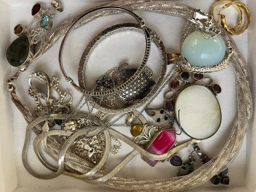 A collection of assorted jewelry, including necklaces, bracelets, and rings, displayed in a white box.
