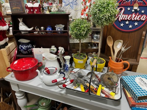 A table filled with various kitchen items, including pots, utensils, plants, and decorative pieces.
