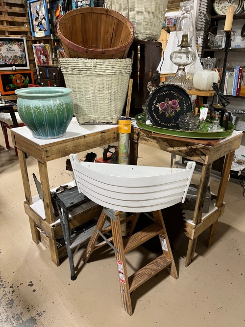 A collection of wooden tables, baskets, and decorative items in a shop setting.