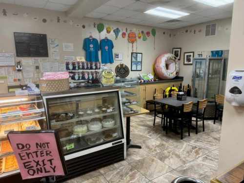A cozy bakery interior with a display case of desserts, a seating area, and colorful decorations on the walls.