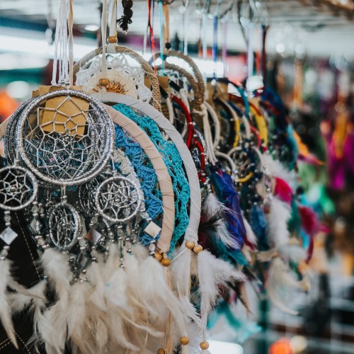 Colorful dreamcatchers with feathers and beads hanging in a display, showcasing intricate designs and vibrant colors.