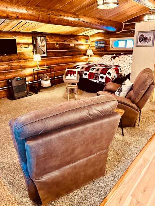 Cozy log cabin interior featuring a seating area, a bed with bear-themed bedding, and warm lighting.