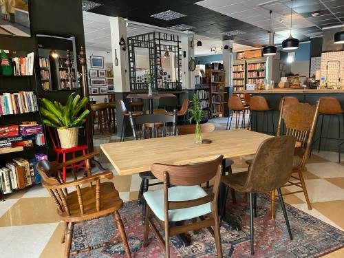 Cozy café interior with wooden tables, chairs, bookshelves, and plants, creating a warm, inviting atmosphere.