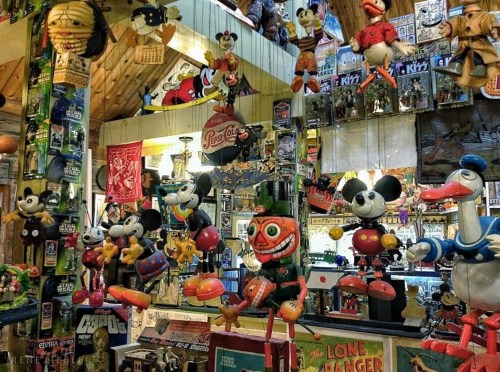 A colorful collection of vintage toys and figurines, including Mickey Mouse and other classic characters, displayed in a shop.