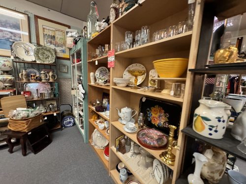 A display of various vintage items and collectibles on wooden shelves in an antique shop.