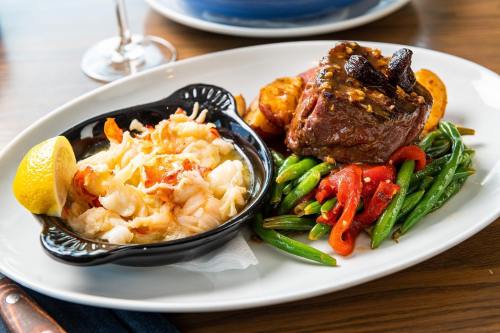 A plate featuring grilled steak, sautéed green beans, roasted potatoes, and a side of shrimp with lemon.