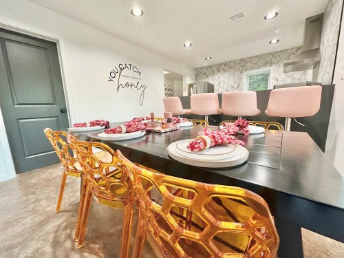 A modern dining area with a black table set for dinner, featuring gold chairs and a stylish wall decor.