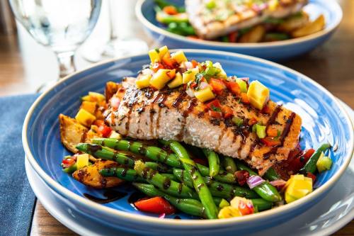 Grilled salmon topped with mango salsa, served on a bed of green beans and roasted potatoes.